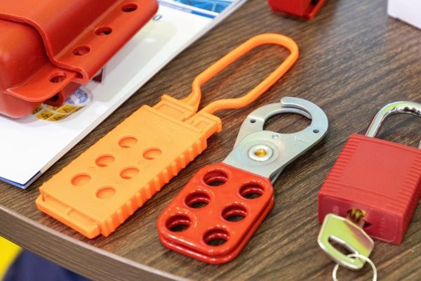 An orange nylon lockout hasp and a steel lockout hasp with a red handle